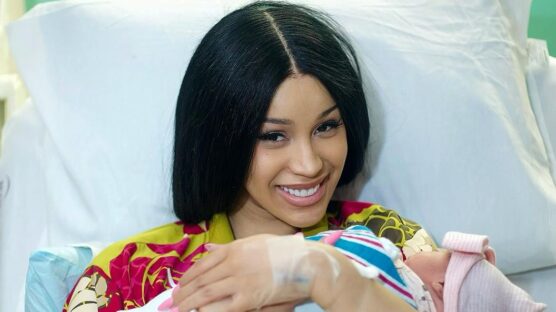 Cardi B holding a baby wrapped in a white flannel