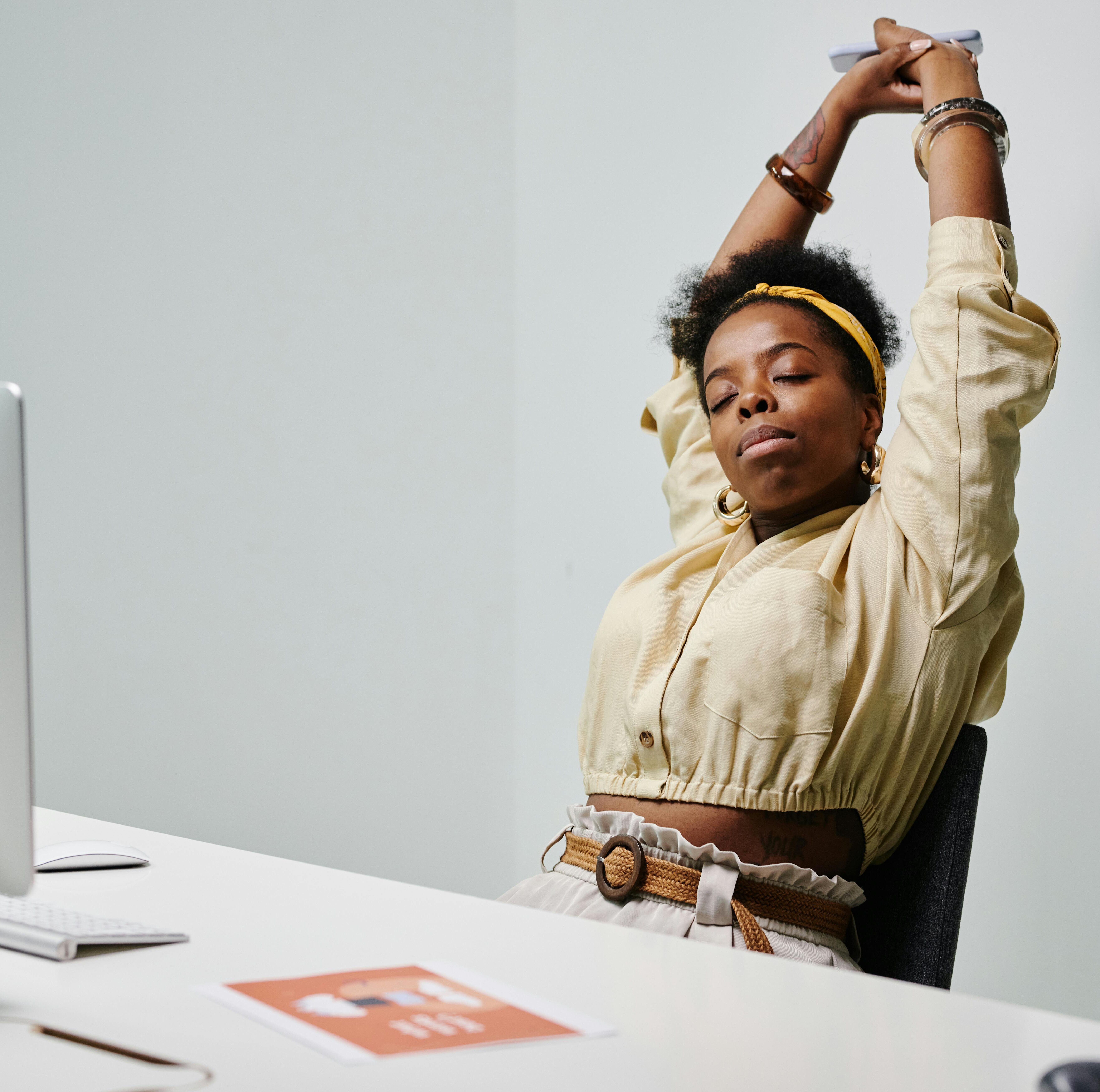 A woman sitting in her office and stretching her arms