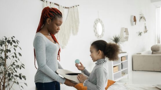 A woman and a girl standing with a small ball on the girl's hand