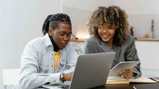 A man and a woman sitting near a table with a laptop at their front