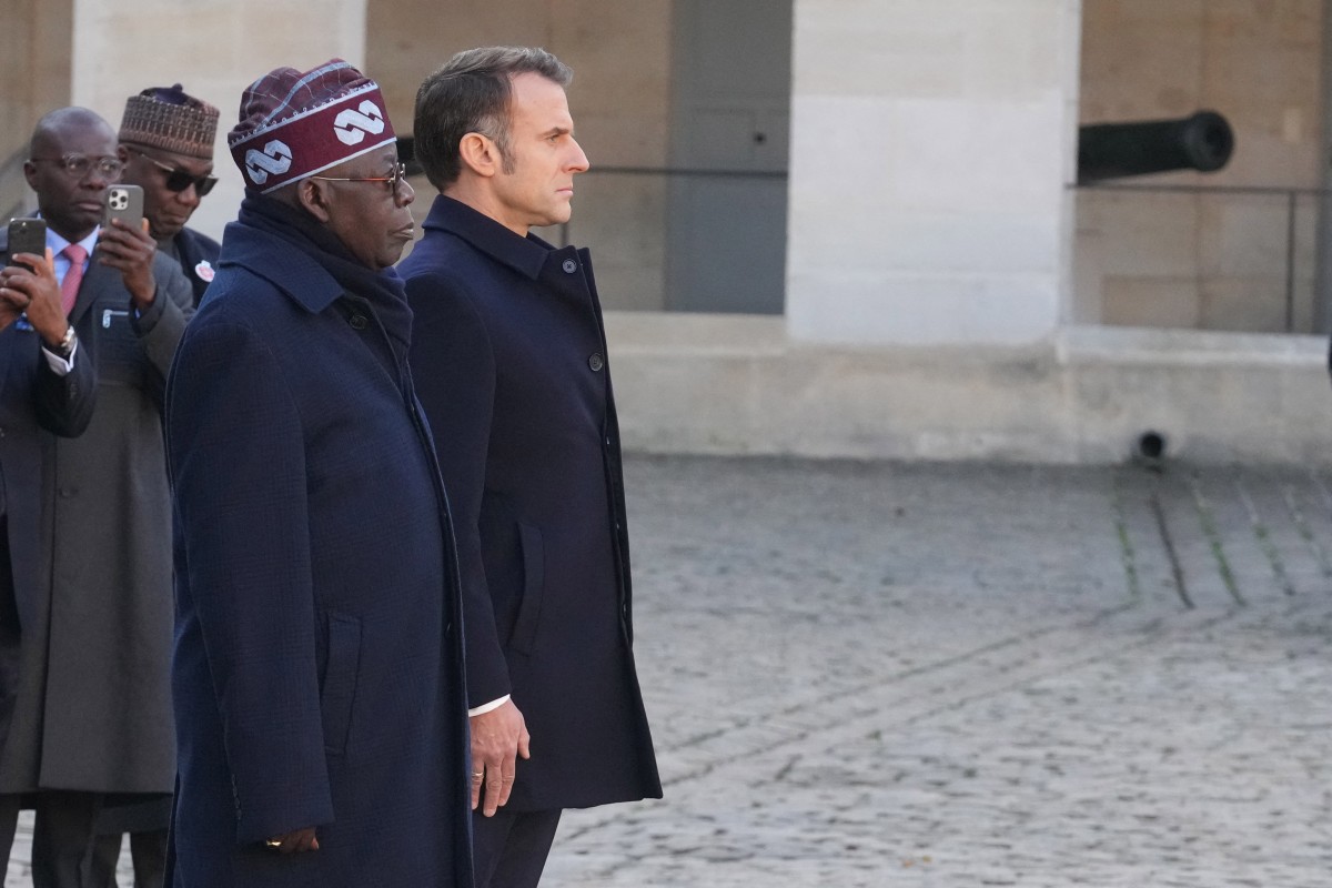 France's President Emmanuel Macron (R) and his Nigerian counterpart Bola Tinubustand at attention during a welcoming ceremony at the Invalides in Paris, on November 28, 2024, as part of Tinubu's state visit to France. (Photo by Michel Euler / POOL / AFP)