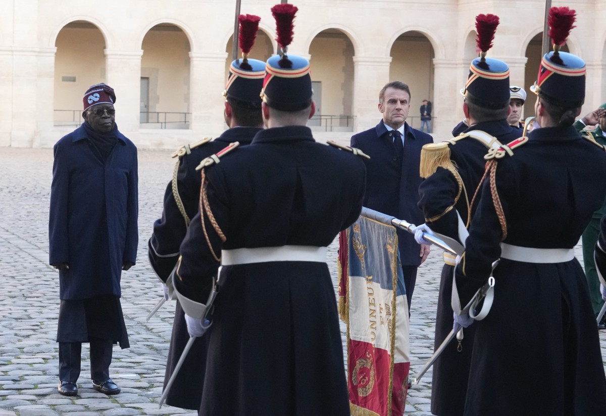 France's President Emmanuel Macron (C) and his Nigerian counterpart Bola Tinubu review a guard of honour during a ceremony at the Invalides in Paris, on November 28, 2024, as part of Tinubu's state visit to France. (Photo by Michel Euler / POOL / AFP)