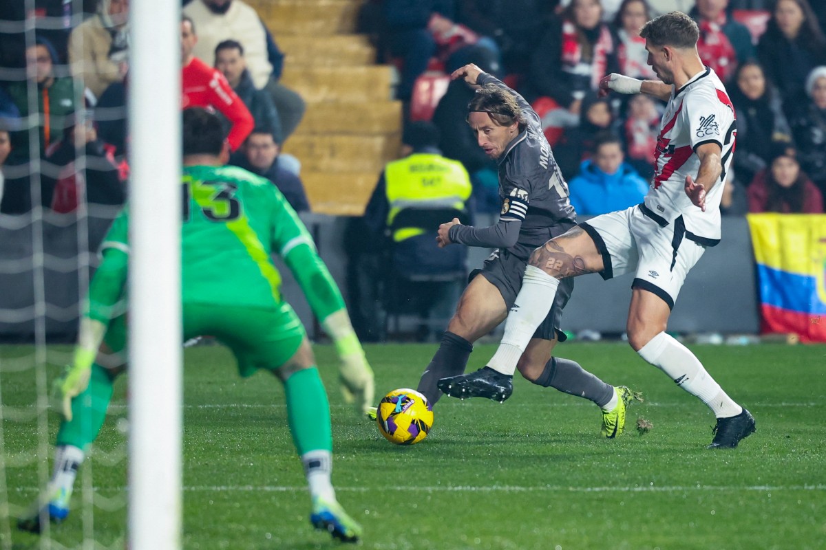 Real Madrid's Croatian midfielder #10 Luka Modric (C) is challenged by Rayo Vallecano's French defender #24 Florian Lejeune during the Spanish league football match between Rayo Vallecano de Madrid and Real Madrid CF at the Vallecas stadium in Madrid on December 14, 2024. (Photo by Pierre-Philippe MARCOU / AFP)